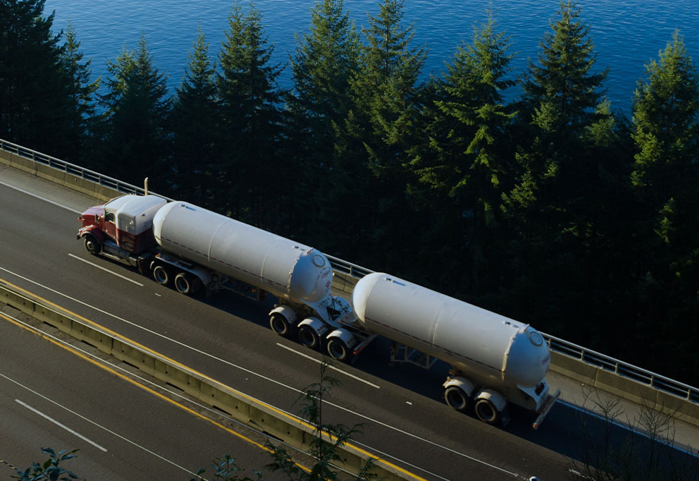 DSN Chemical Transportation carrier partner double tanker truck driving on North American highway alongside lake