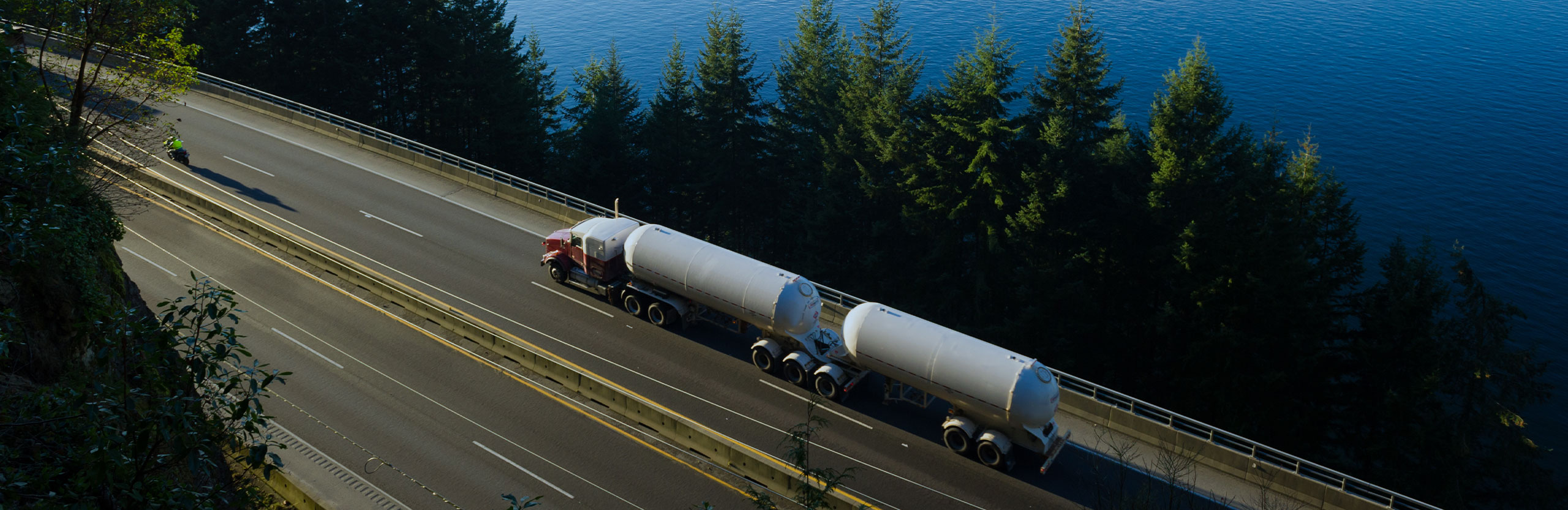 DSN Chemical Transportation carrier partner double tanker truck driving on North American highway alongside lake